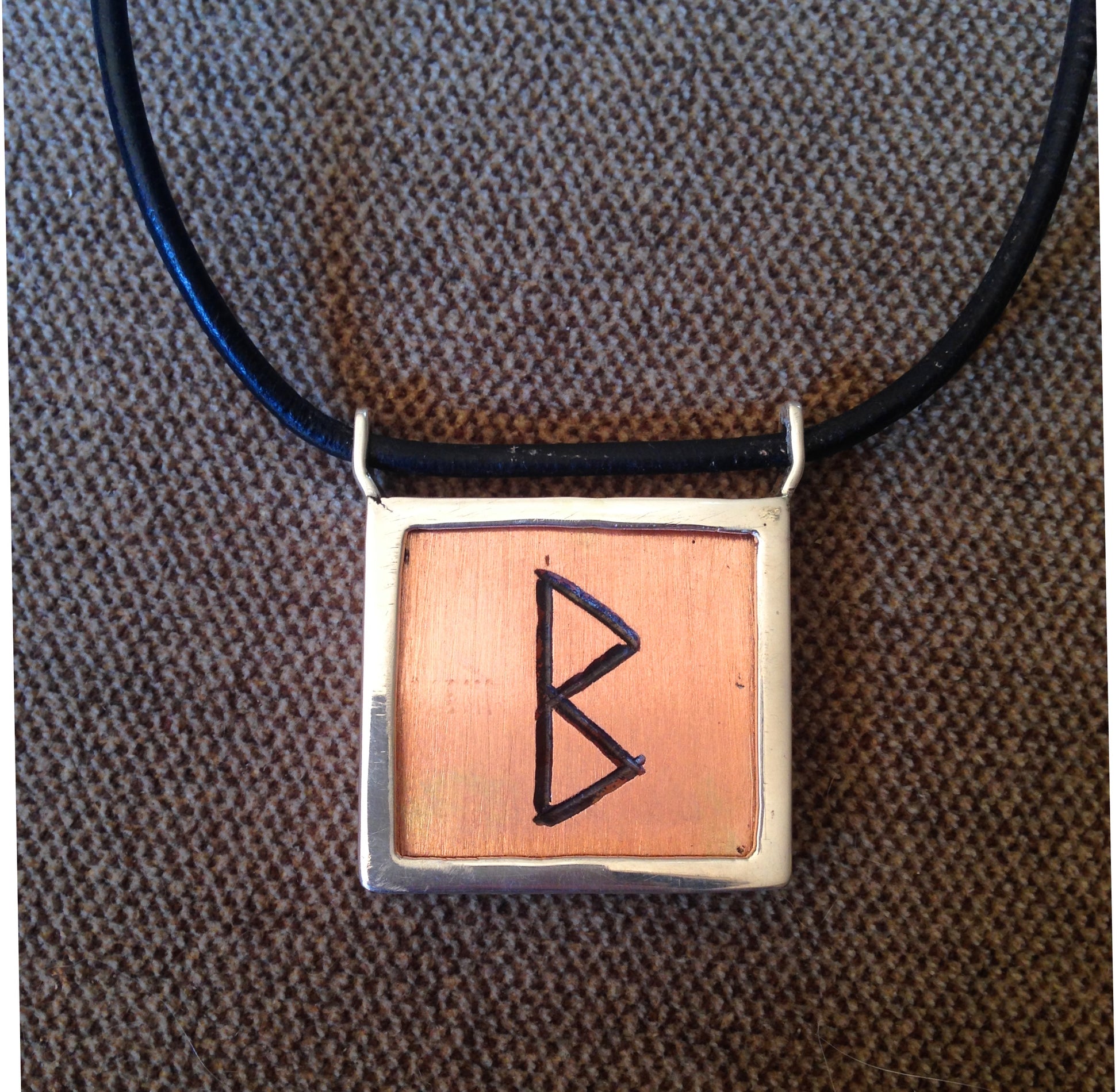 Heavy solid copper rune in silver frame